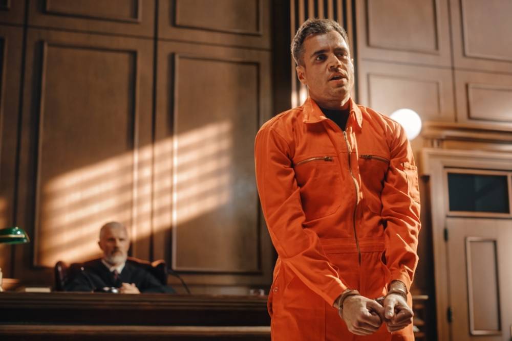 Portrait of Accused Male Criminal in Orange Jumpsuit Giving Testimony to Judge