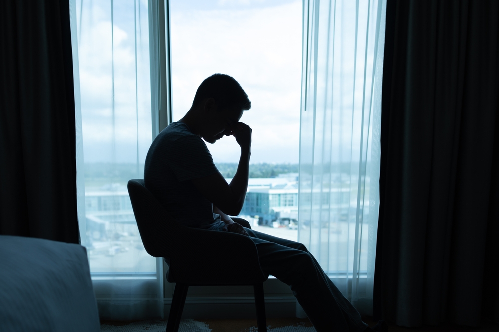 Portrait of tired stressed man alone in a dark room. Fear, sadness, abuse, depression, addiction.
